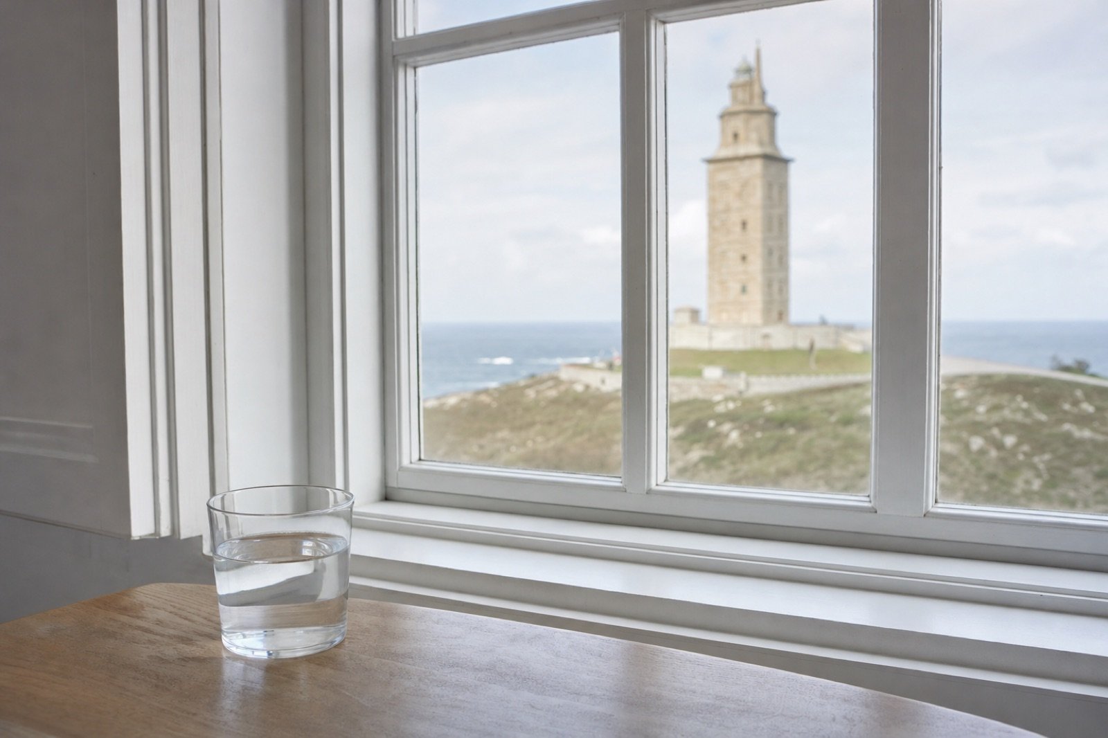 Vaso de agua junto a una ventana con vistas a la Torre de Hércules